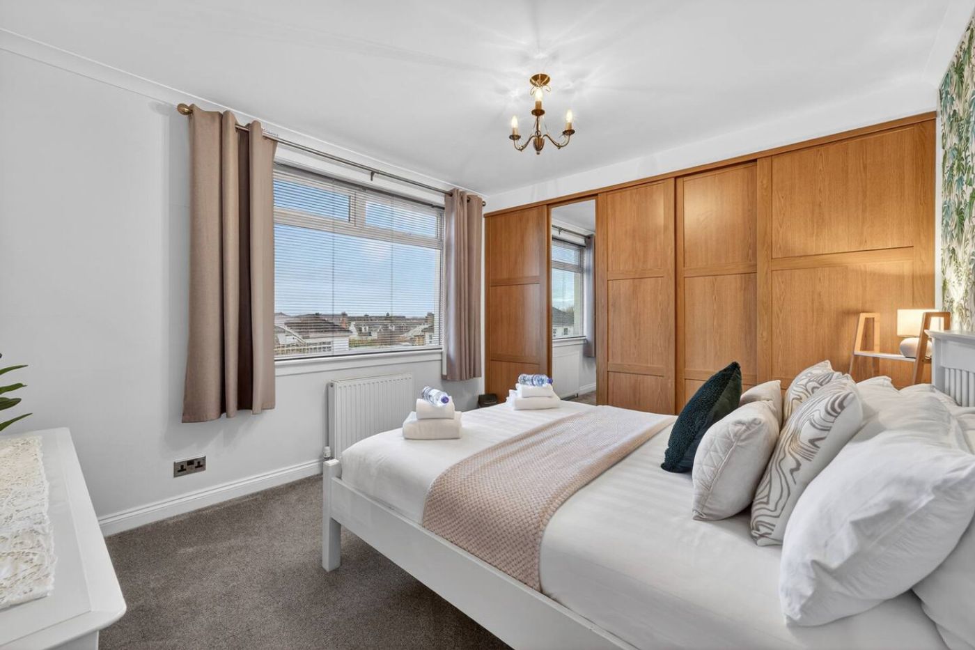 A double bedroom with botanical wallpaper and a built-in wardrobe.