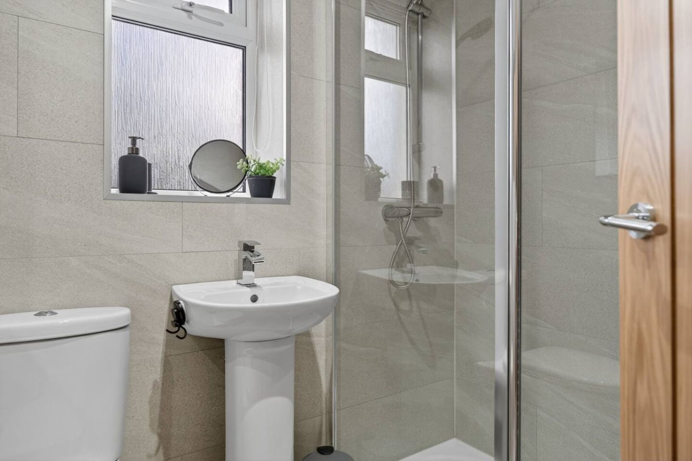 The bathroom: pedestal sink and a glass shower.